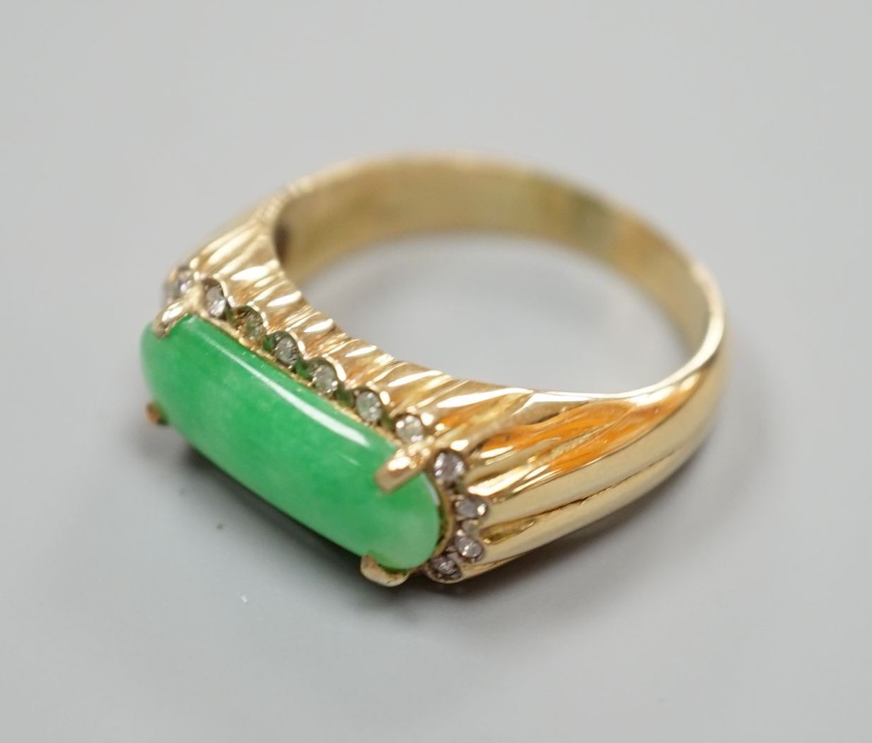 A yellow metal, jadeite and diamond set ovoid dress ring, size T, gross 6.6 grams.